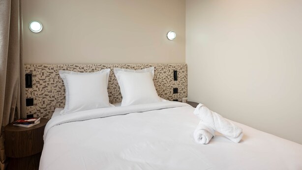 A hotel room with a neatly made bed, two bedside tables, and a headboard with a geometric pattern. - Deluxe Suite between Concorde and Vendôme (Paris)