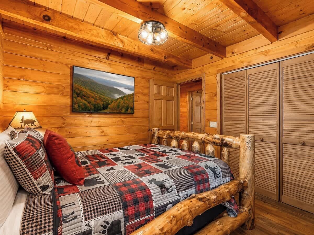 Une pièce chaleureuse, avec des murs en bois, un lit, une lampe et un tableau représentant un paysage.