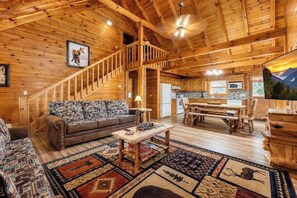 Ein Holzblockhaus-Interieur mit einer Couch, einem Couchtisch und einem Essbereich.