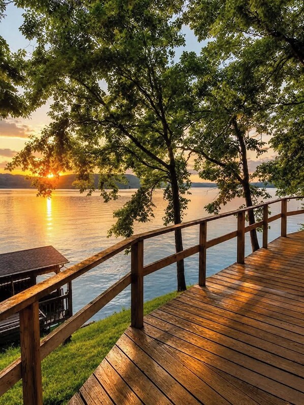 A wooden deck overlooking a calm lake with a sunset in the background.
