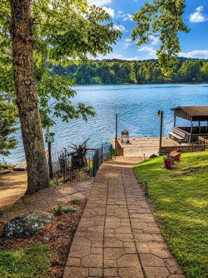 A wooden dock extending into a lake, surrounded by trees and a grassy area.
