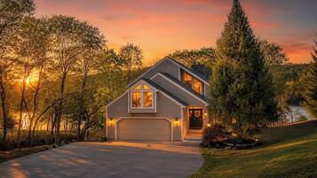 A single-story house with a garage, surrounded by trees and a driveway.