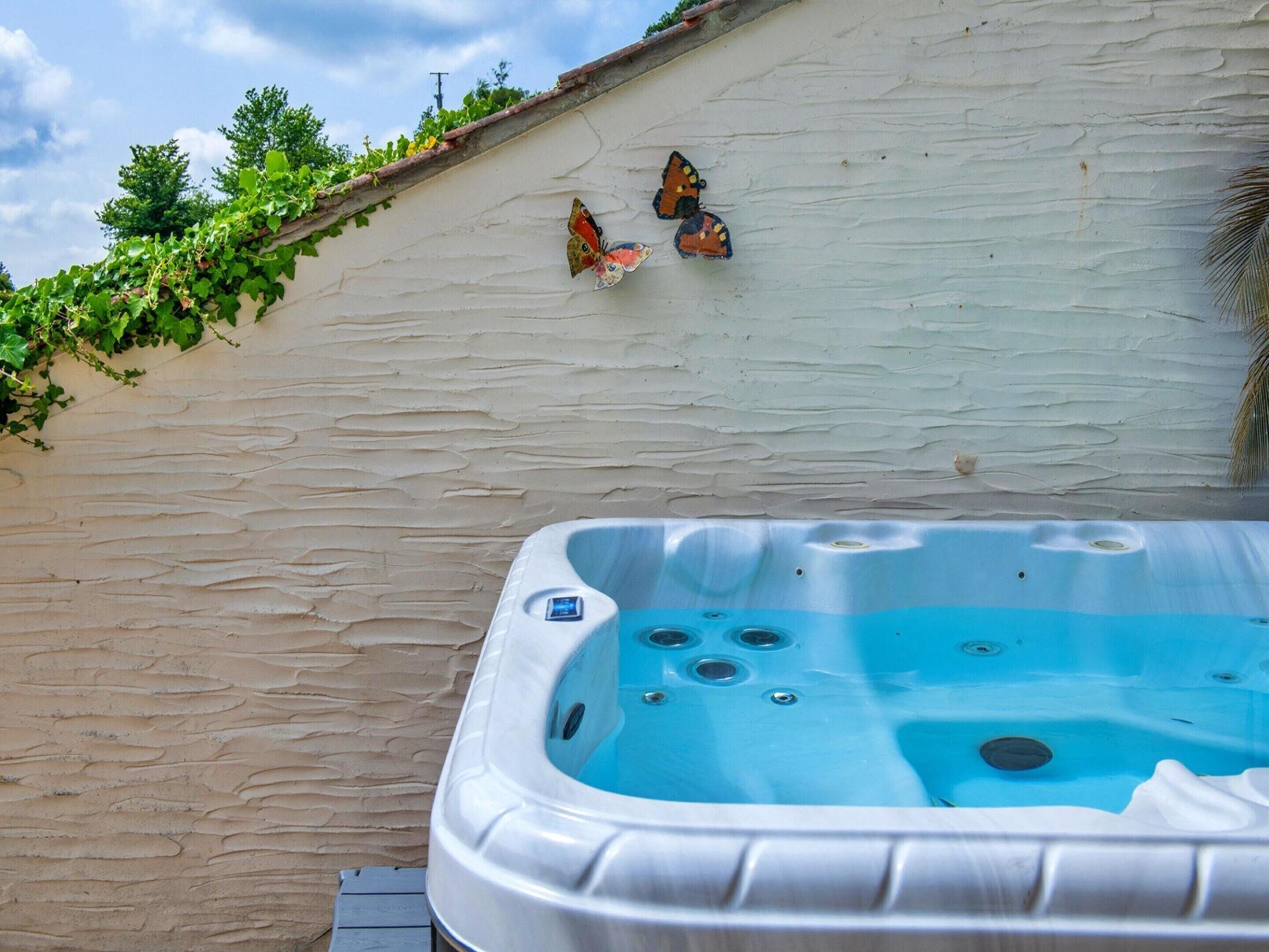 A hot tub adjacent to a textured wall with a small garden area above.