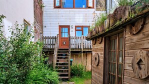 A narrow alleyway with a wooden staircase leading to a white building with two visible windows and a door. - Waterfront Escape With Deck (Torpoint)