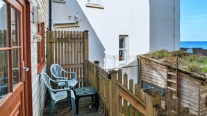 A narrow outdoor space with a wooden fence, a small table, and two chairs. - Waterfront Escape With Deck (Torpoint)
