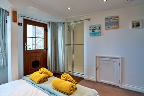 Ein Hotelzimmer mit einem Bett, einer Dusche, einer Tür und einem kleinen Schrank.
