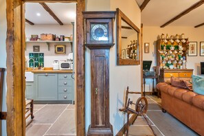 A traditional kitchen with a wooden door, a large grandfather clock, and a vintage bicycle. - Holiday Cottage in Llangadog (Llangadog)