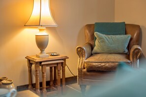 Ein Ledersessel mit Kissen, ein Holztisch mit Lampe und eine kleine Schale.