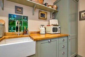 Eine Küche mit Holzarbeitsplatte, einem weißen Spülbecken, einer Mikrowelle und einem Schrank mit Schubladen.