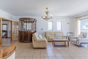 A spacious living room with a large wooden cabinet, a beige sofa, a coffee table, and a chandelier. - #416 Spacious Villa | Private Pool, BBQ, and Parking (Albufeira)