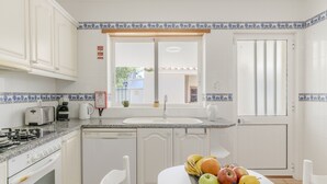 A kitchen with white cabinets, a granite countertop, a stove, a sink, and a window with a view of the outside. - #416 Spacious Villa | Private Pool, BBQ, and Parking (Albufeira)