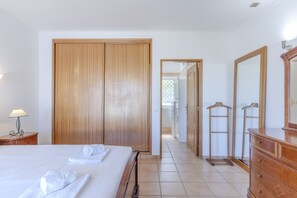A hotel room with a bed, a wooden wardrobe, a dresser, and a mirror. - #416 Spacious Villa | Private Pool, BBQ, and Parking (Albufeira)