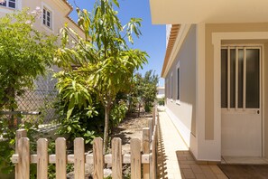 Um imóvel residencial com cerca de madeira, um caminho e um edifício com porta branca.