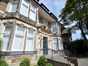 A two-story stone building with multiple windows and a black metal railing in front. - Harrogate Apartment Near Bettys (Harrogate)