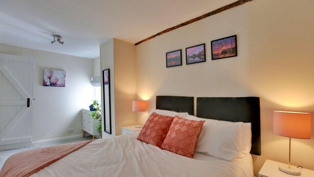 Un dormitorio con cama, mesitas de noche, lámpara, ventilador de techo y una puerta.