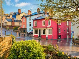 A street view with colorful houses, a cyclist, and a wet road.