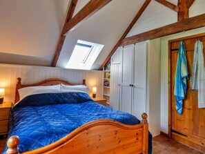 Ein Schlafzimmer mit einem Holzbett, einem Oberlicht, einem Kleiderschrank und einem aufgehängten Handtuch.