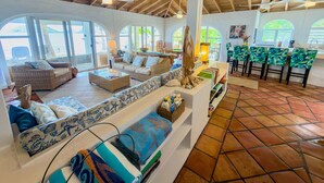 A spacious living area with a high ceiling, large windows, and a kitchen area with bar stools. - Beautiful Private Waterfront Estate, 2 Properties, 4 Bedrooms, West End Tortola (Tortola)