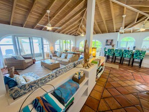 A spacious living area with a high ceiling, large windows, and a kitchen area with bar stools. - Beautiful Private Waterfront Estate, 2 Properties, 4 Bedrooms, West End Tortola (Tortola)