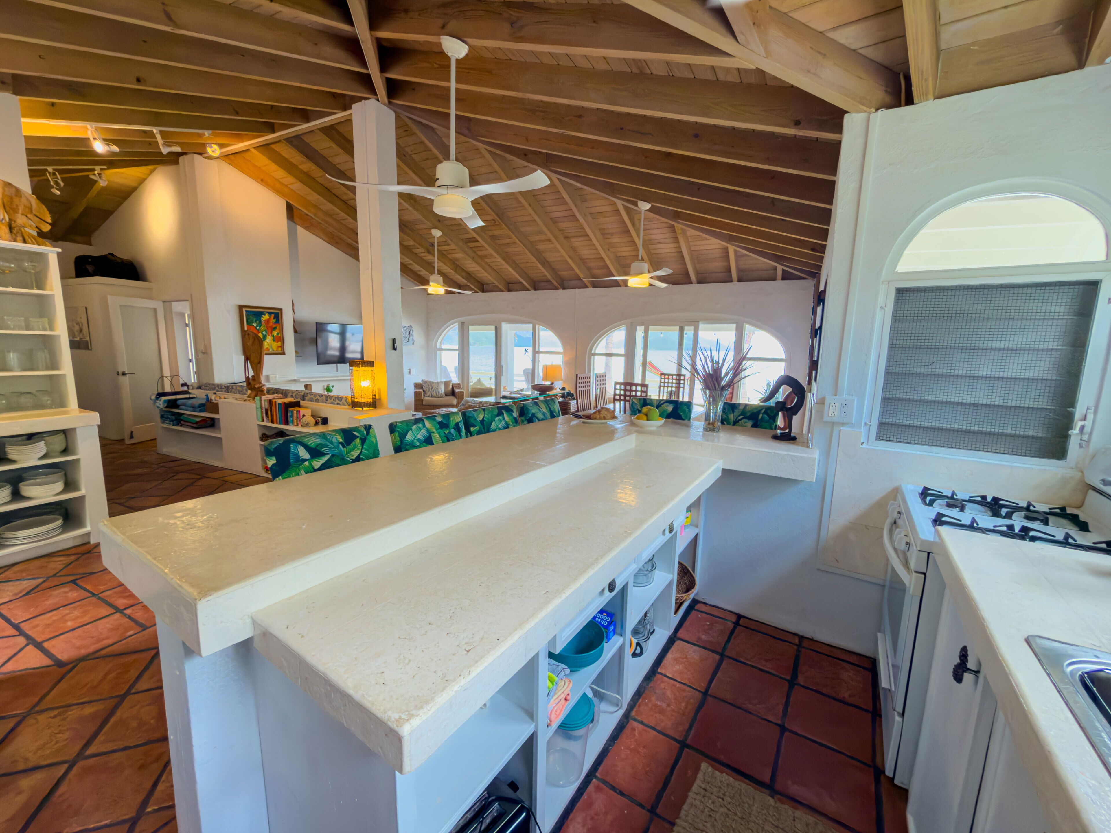 A spacious kitchen with a large island, a dining area with a view, and a living room with a television.