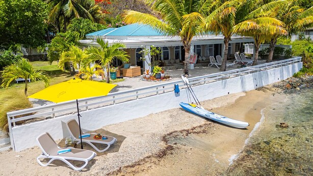 A beachside property with a covered seating area, lounge chairs, and a kayak. - Beautiful Private Waterfront Estate, 2 Properties, 4 Bedrooms, West End Tortola (Tortola)