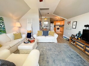 Ein Wohnzimmer mit einem weißen Sofa, einem Couchtisch und einer TV-Konsole mit einem Flachbildfernseher.
