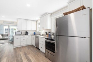 Eine moderne Küche mit weißen Schränken, Edelstahlgeräten und einem großen Kühlschrank.