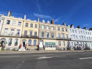 A row of terraced houses with a shop on the ground floor. - 123 On The Sea The Eaves (Weymouth)