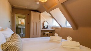Een slaapkamer met een groot bed, een bureau met een spiegel en een raam.