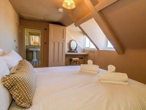 A bedroom with a large bed, a desk with a mirror, and a window. - 123 On The Sea The Eaves (Weymouth)