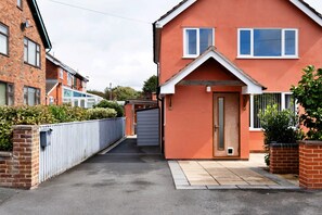A residential property with a red facade, a front door, and a small front yard. - Countryside Escape Near Hergest Ridge (Kington)