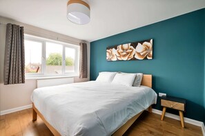 A bedroom with a bed, a nightstand, a window with curtains, and a wall-mounted artwork. - Countryside Escape Near Hergest Ridge (Kington)