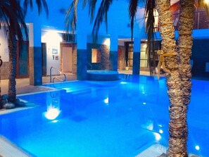 An indoor swimming pool with a clear water surface, surrounded by palm trees and a stone wall. - Countryside Escape Near Hergest Ridge (Kington)