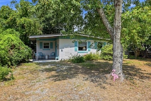 A single-story house with a porch, a small deck, and a tree in front. - Seabright Surf Shack | Oak Island Beach Bungalow by Brunswick Vacation Rentals (Oak Island)