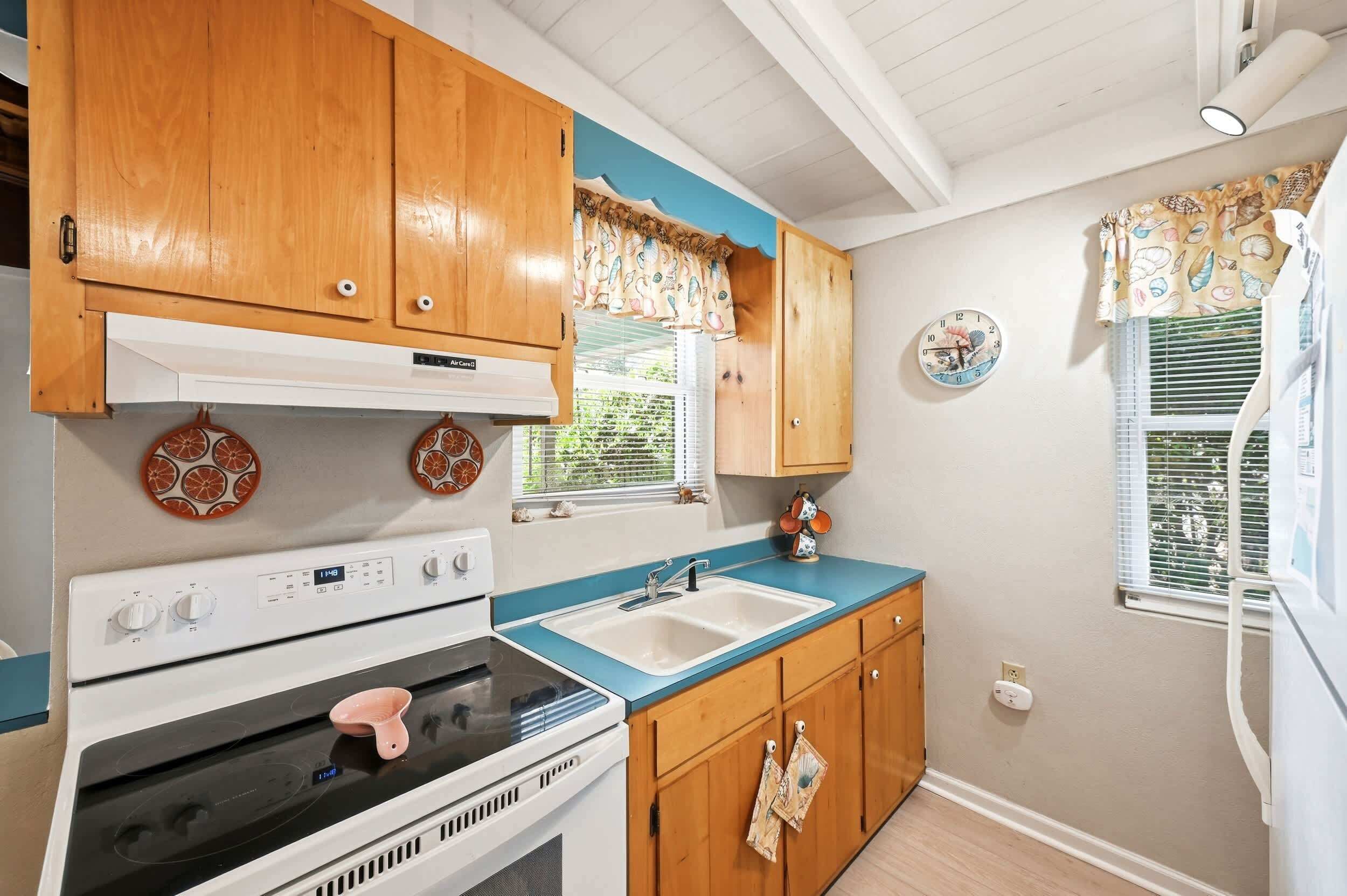 Une cuisine avec des meubles de rangement en bois, une cuisinière, un évier et une horloge au mur.