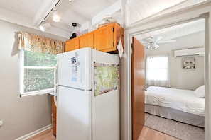 Ein kleines Zimmer mit einem Bett, einem Kühlschrank und einem Fenster mit Jalousien.