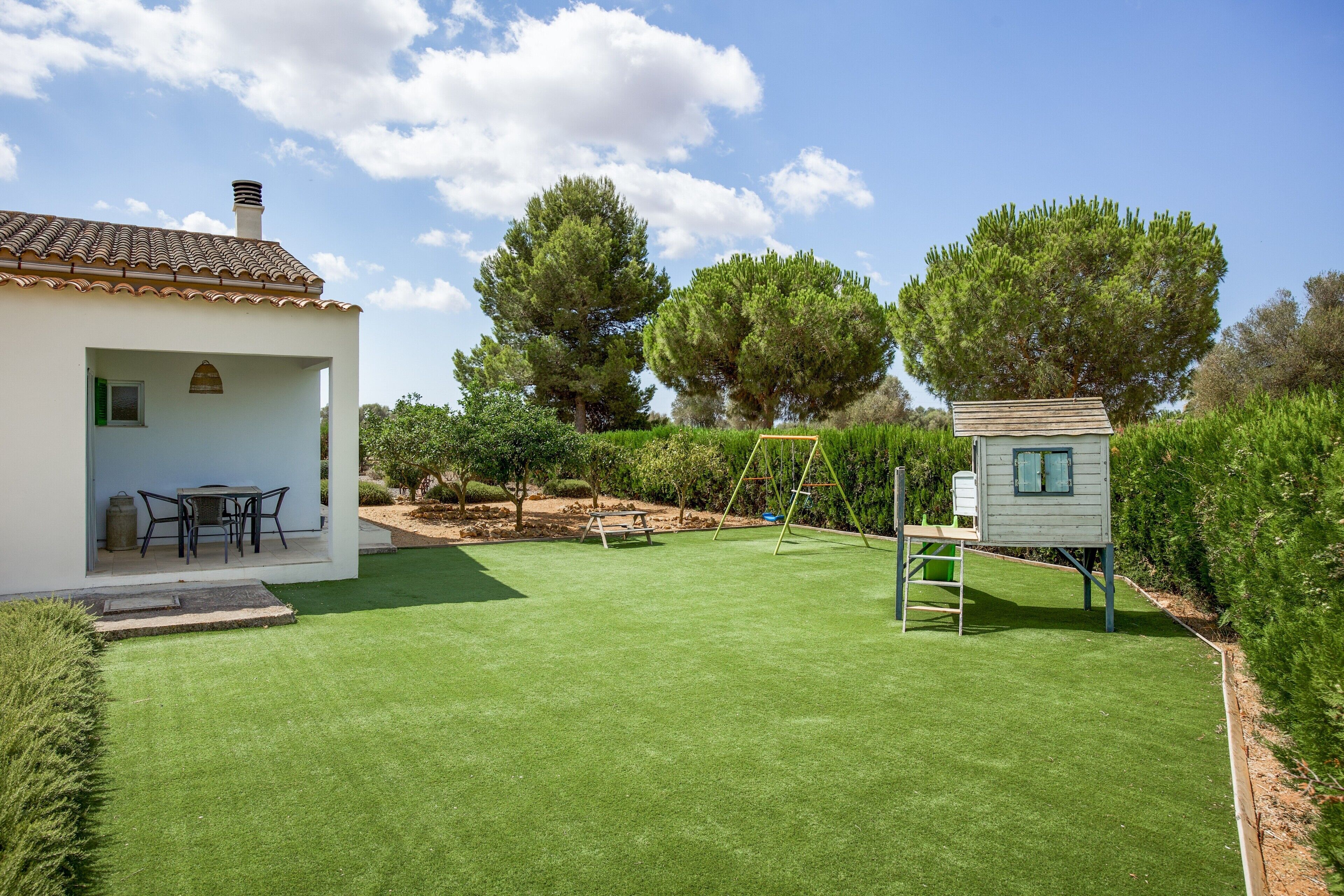 Una propiedad residencial con patio, una casita de juegos y un césped bien cuidado.