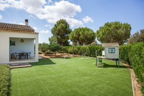 Una propiedad residencial con patio, una casita de juegos y un césped bien cuidado.