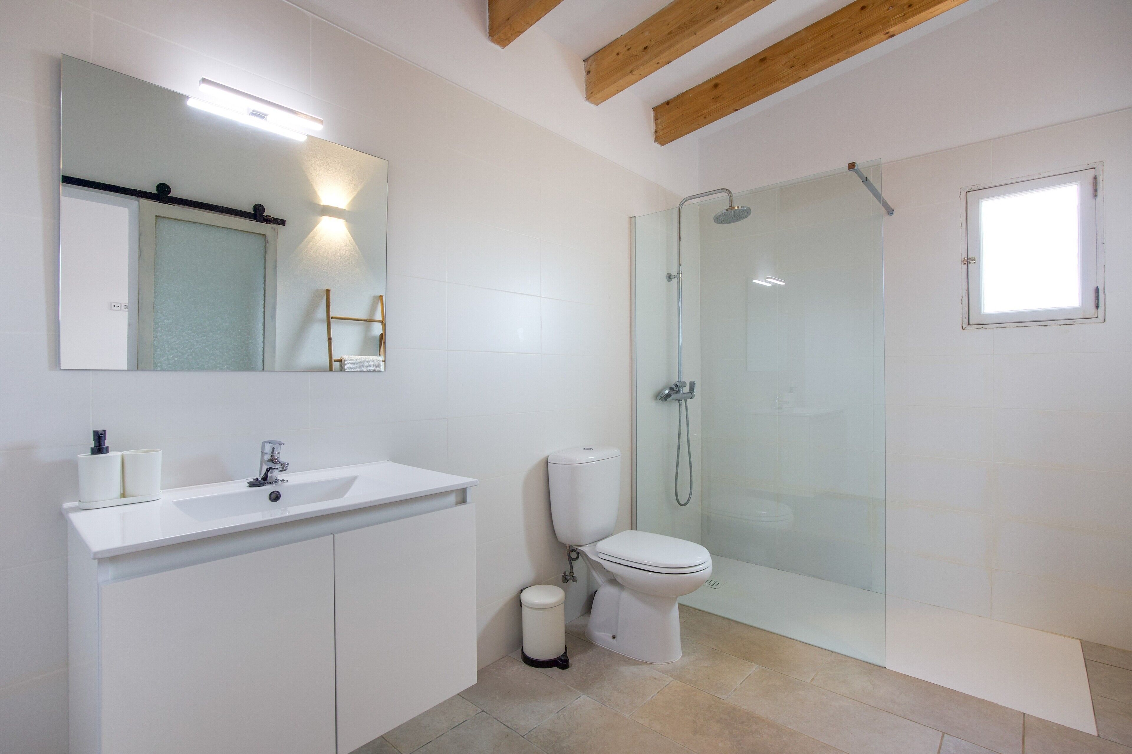 Een moderne badkamer met een glazen douchecabine, een wit wastafelmeubel en een toilet.