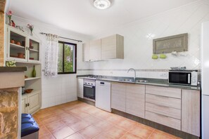 Una cocina compacta con armarios blancos, horno empotrado, microondas y pileta.