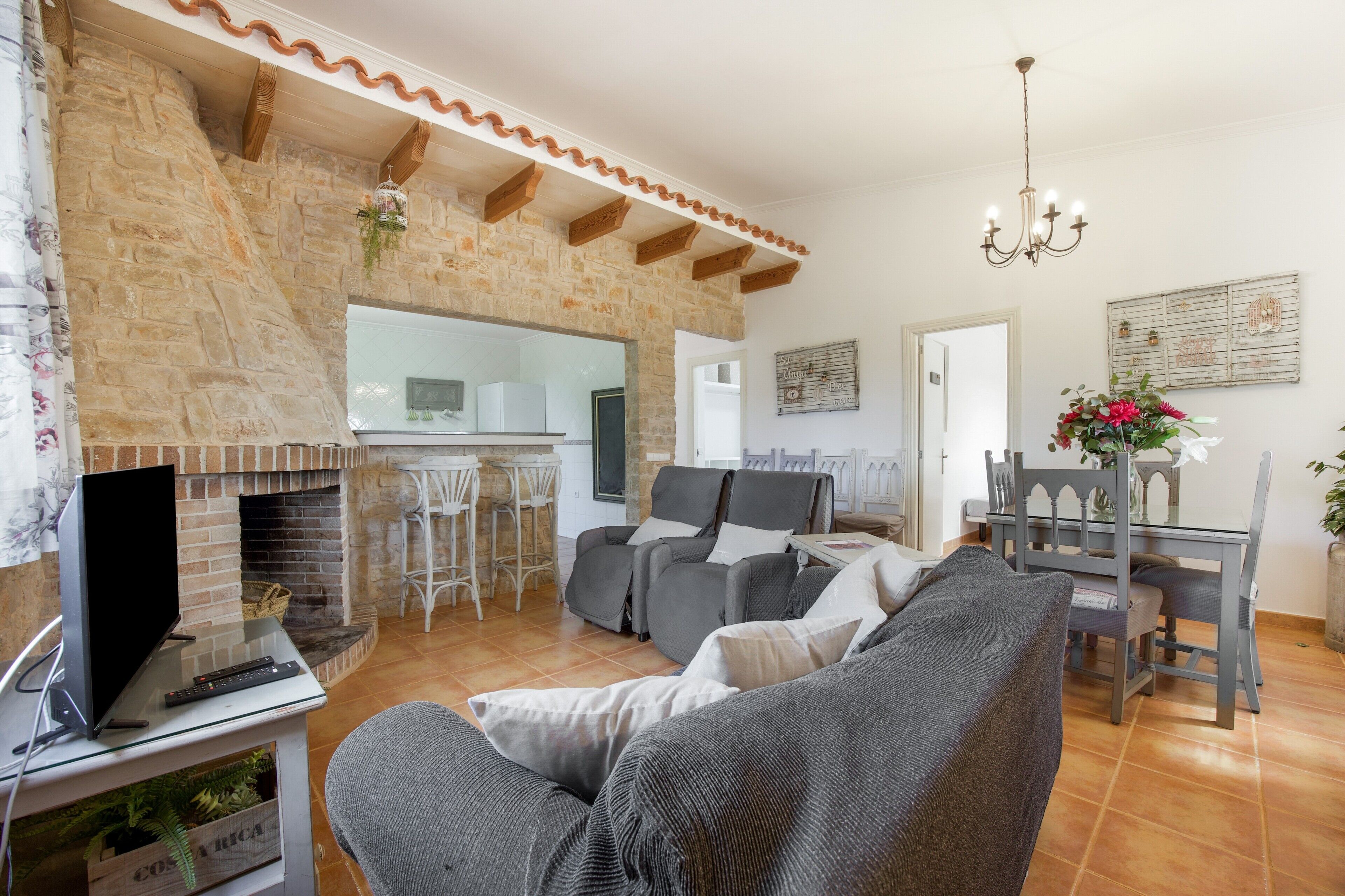 Una sala de estar con chimenea, un sofá, un televisor y un comedor.