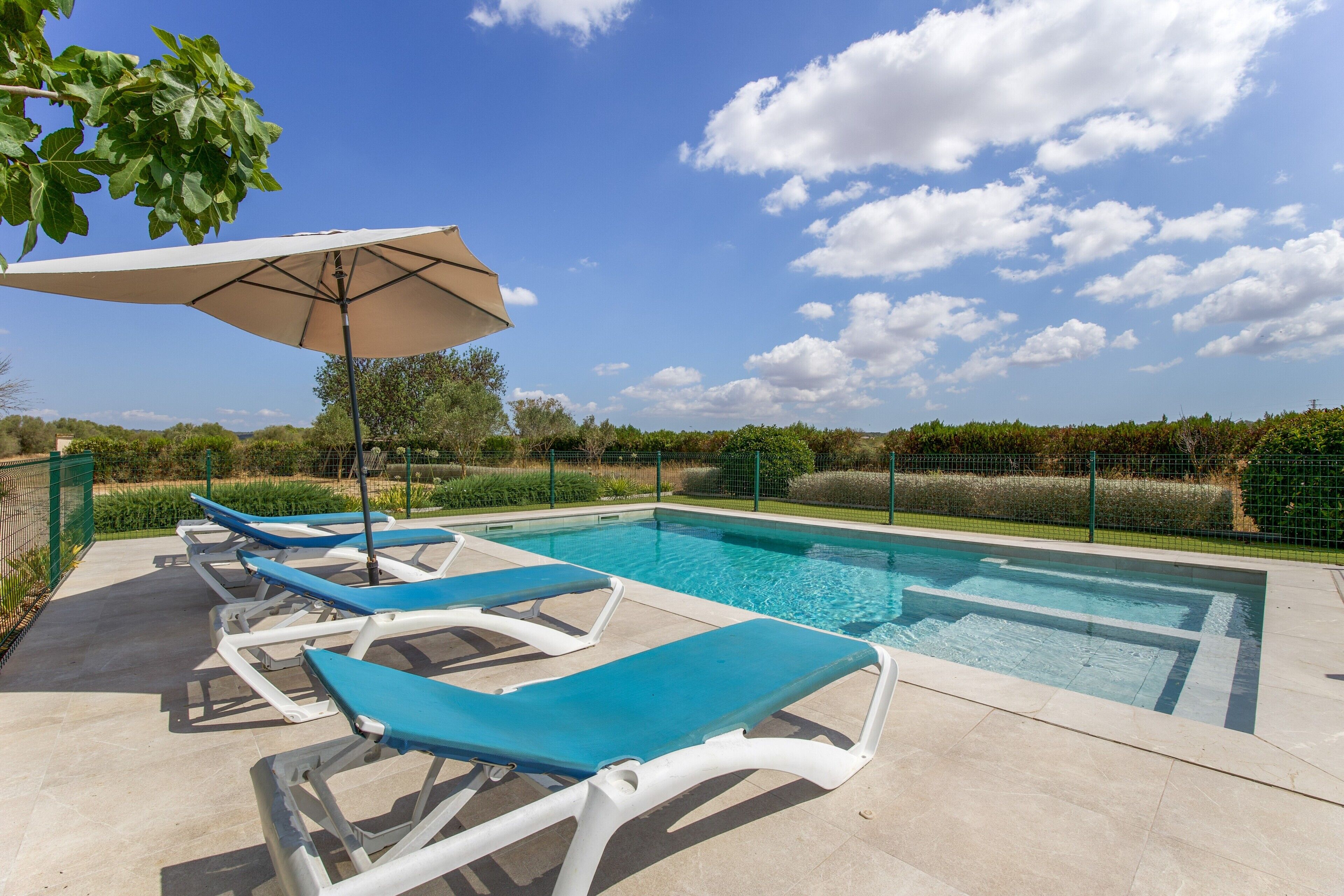 Una piscina con sillones de descanso y una sombrilla.