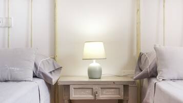 A simple, clean room with two beds, a bedside table with a lamp, and a wall-mounted light switch.