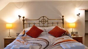 A bed with a patterned bedspread, two pillows, and two bedside lamps. - Nice Cottage in High Bickington (Umberleigh)