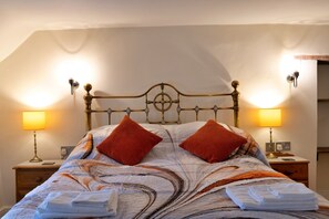 Ein Bett mit einem gemusterten Überwurf, zwei Kissen und zwei Nachttischlampen.