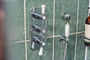 Ein Badezimmer mit einer fest installierten Duschsteuerung und einer Handbrause.