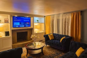 A living room with a fireplace, a television, and two sofas with yellow cushions. - Executive 4BR Home Fully Furnished. CALL IT HOME 30+Day (Louisville)