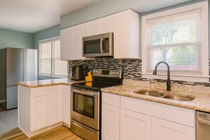 A kitchen with white cabinets, a stainless steel refrigerator, a microwave, a stove, and a sink. - Executive 4BR Home Fully Furnished. CALL IT HOME 30+Day (Louisville)