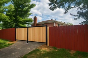 A residential property with a gated entrance, a red picket fence, and a house with a chimney. - Executive 4BR Home Fully Furnished. CALL IT HOME 30+Day (Louisville)