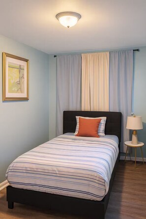 A bedroom with a bed, a nightstand, a lamp, and a framed picture on the wall. - Executive 4BR Home Fully Furnished. CALL IT HOME 30+Day (Louisville)